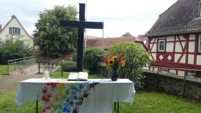Ein Tisch mit Blumen und Kreuz im Garten, umgeben von Häusern
