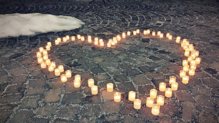 Leuchtende Kerzen in Herzform auf Kopfsteinpflaster angeordnet