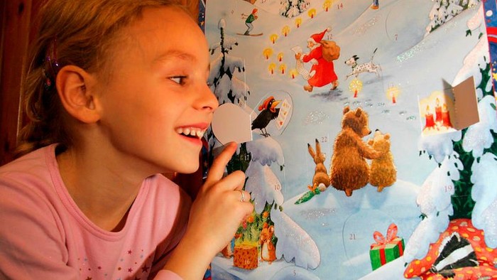 Ein Mädchen hält ein Telefon und schaut ein Adventskalenderbild an