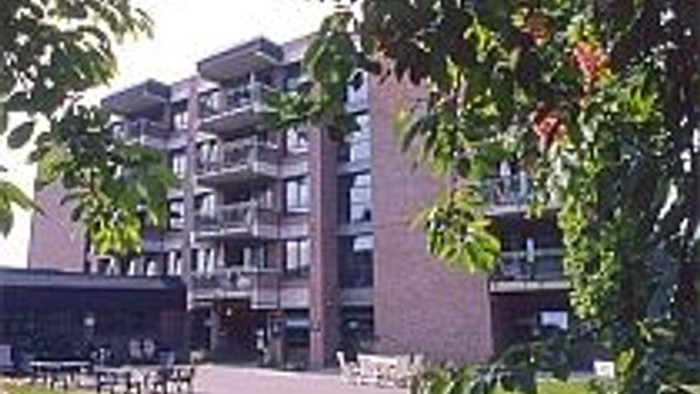 Ein modernes Gebäude mit vielen Fenstern und Bäumen davor.