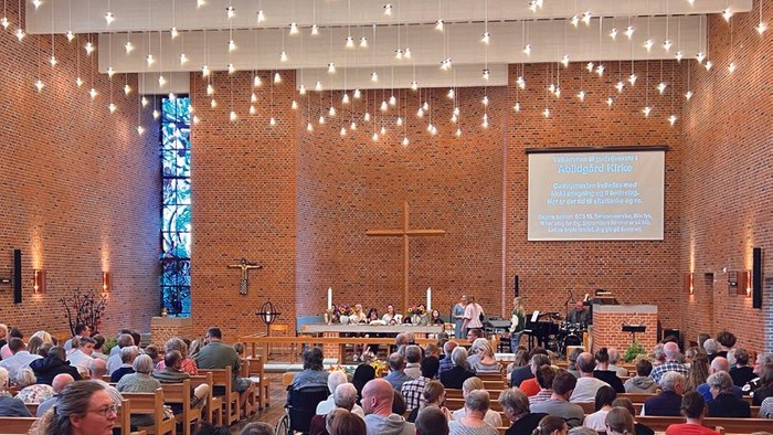 En stor kirke med mange tilstedeværende, lys og en prædikestol.