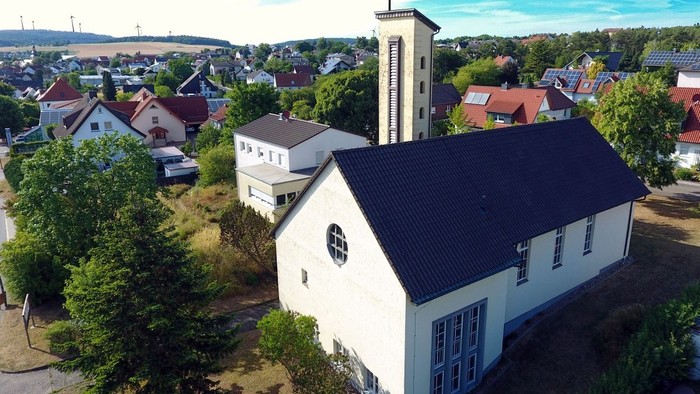 Luftaufnahme einer weißen Kirche mit hohem Kirchturm in einer Kleinstadt.