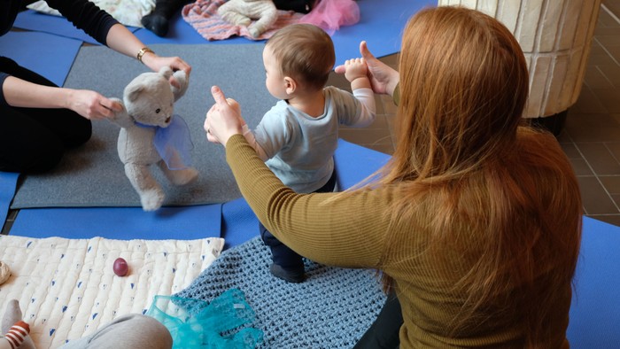 Gruppe af spædbørn og omsorgspersoner, der deltager i en babysprogstegn- eller interaktiv legeseance.