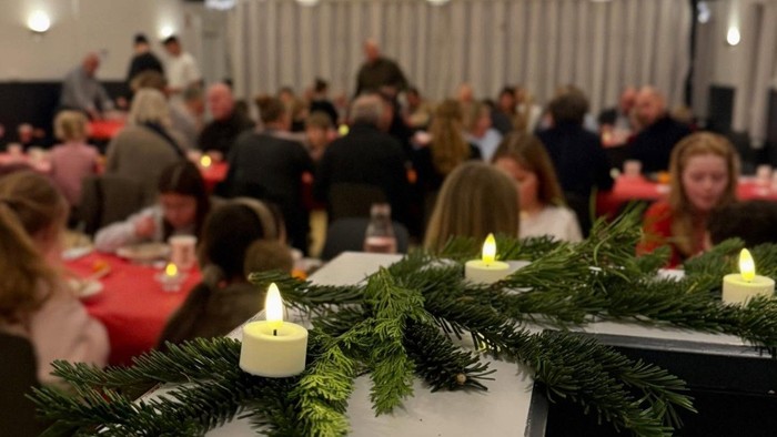 Stemningsbillede fra Ishøj forsamlingshus, hvor børnene fra Ishøj skole nyder risengrød efter årets krybbespil i kirken. I forgrunden ses grangrene med lys på.