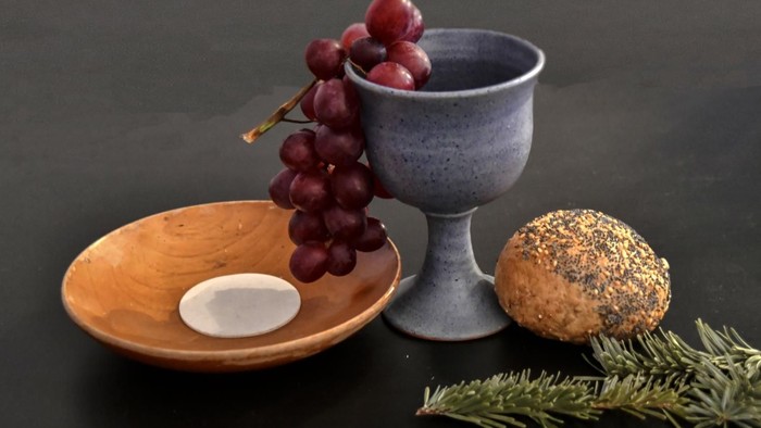 Weinkelch und Hostienschale mit Körberbrötchen als rustikales, stilistisch ausgefeiltes Sinnbild für die Kommunion