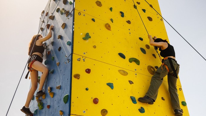 Zwei Jugendliche klettern an einem Kletterturm