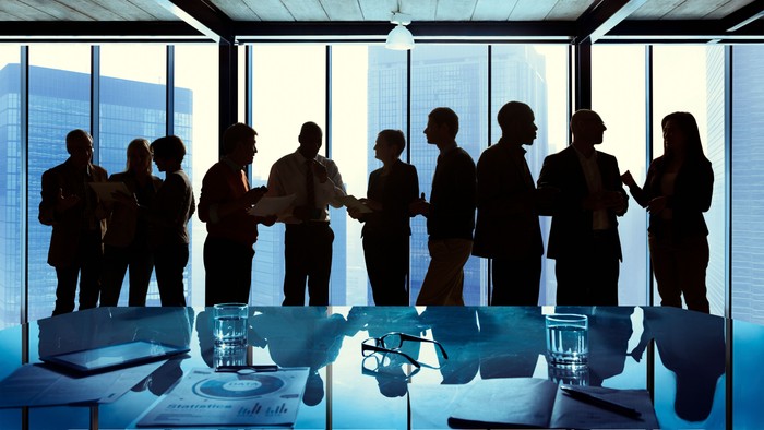 silhouettes of people talking next to a boardroom table 