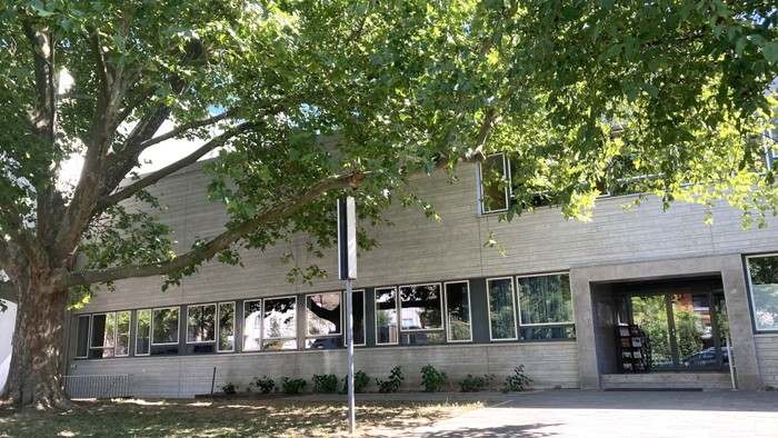 Modernes Gemeindehaus mit Baum davor.