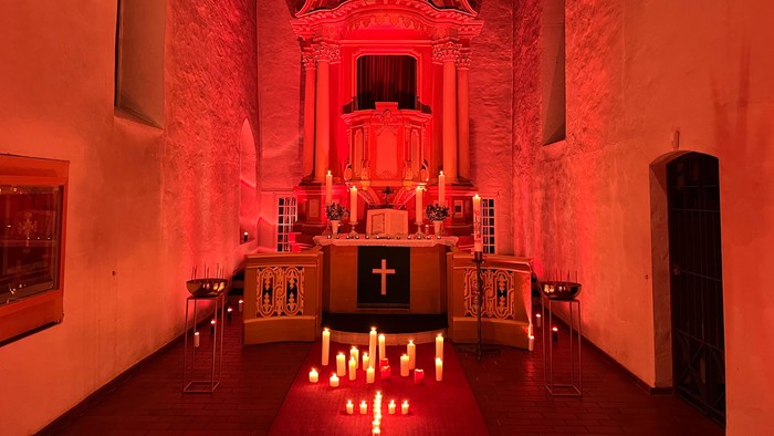 Kirchlicher Altarraum mit Kerzenlicht und Kreuzigungsgruppe