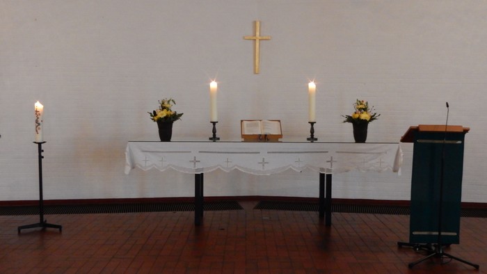 Ein Altar mit Kerzen, Blumen und Kreuz in einem Raum
