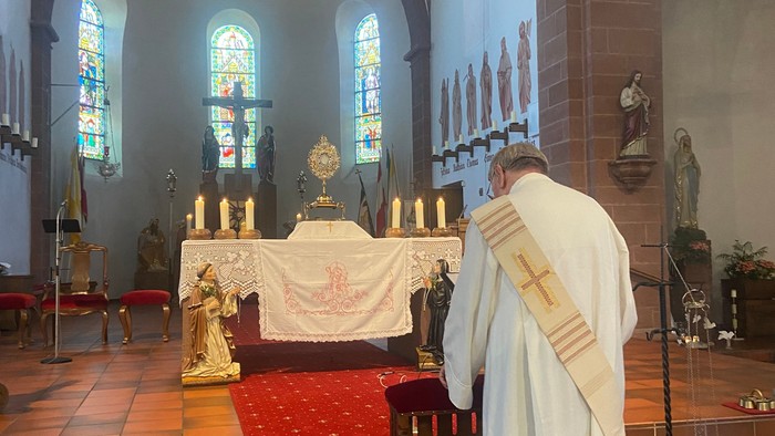 Priester in weißen Gewändern, der sich in einer wunderschön geschmückten Kirche auf einen Gottesdienst vorbereitet.