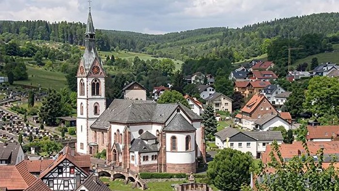 Bezauberndes Dorf mit einem markanten Kirchturm, eingebettet in saftig grüne Hügel und umgeben von malerischen Häusern.