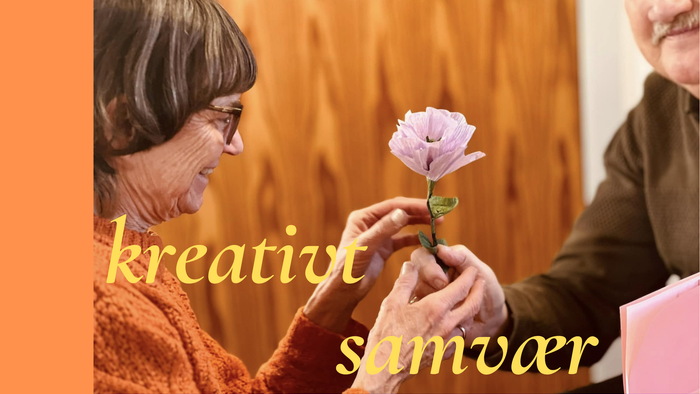 To ældre personer, der kreativt interagerer med et lille blomsterarrangement, mærket *