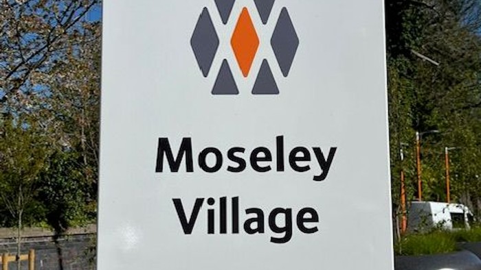 Signpost marking Moseley Village station with Network Rail and local council logos.
