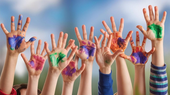 Bunte Kinderhandabdrücke vor einem hellen Himmel im Freien.