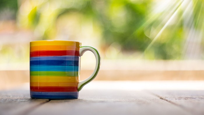 Bunter Becher mit Griff auf hellem Tisch bei Tageslicht