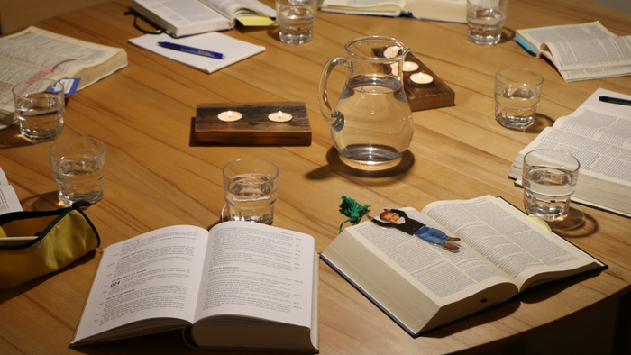 Ein Tisch mit offenen Büchern, Gläsern und einer Teekanne.