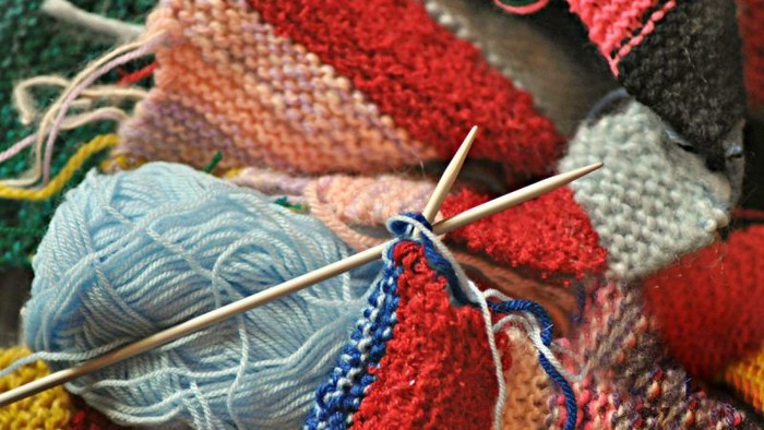 En bunt med strå og knittingtråder i forskellige farver.
