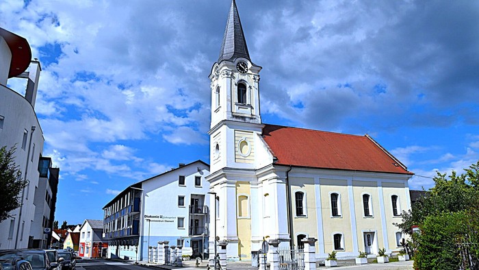 Kirchengemeinde mit weißem Turm und rotem Dach in kleiner Stadt