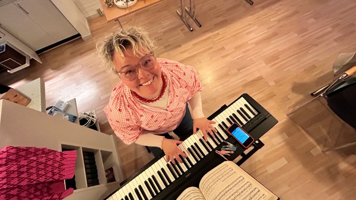 Kvinde, der spiller keyboard med en åben bog foran sig.