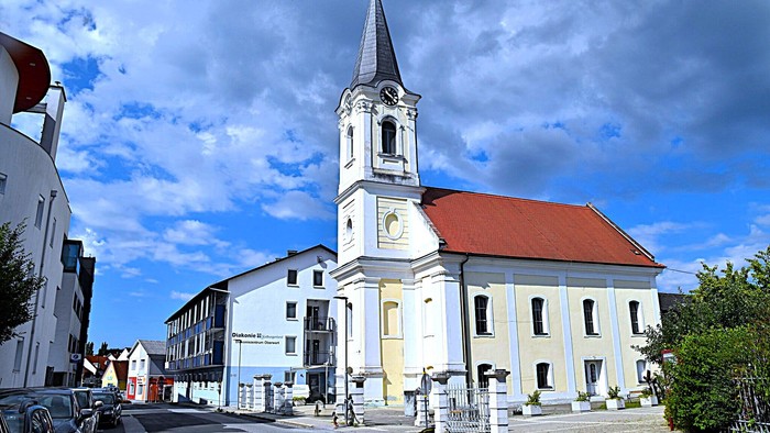 Kirchengemeinde mit weißem Turm und rotem Dach in kleiner Stadt