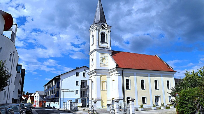 Kirchengemeinde mit weißem Turm und rotem Dach in kleiner Stadt