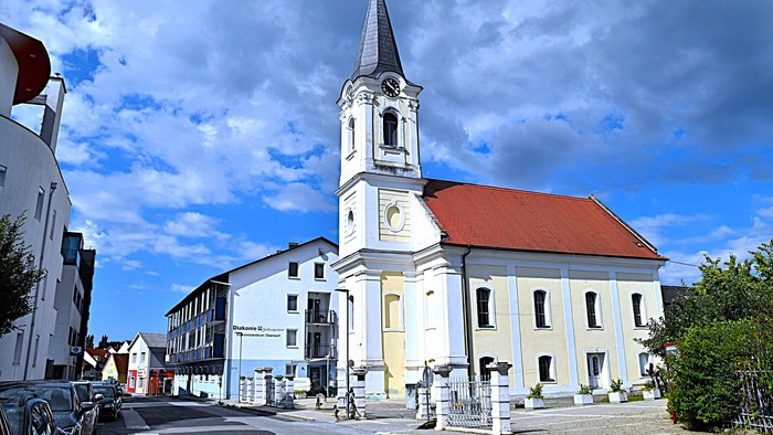 Kirchengemeinde mit weißem Turm und rotem Dach in kleiner Stadt
