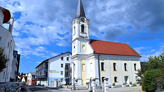 Kirchengemeinde mit weißem Turm und rotem Dach in kleiner Stadt