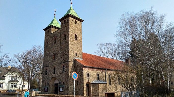 Alte Kirche mit zwei Türmen und rotem Dach an der Straße