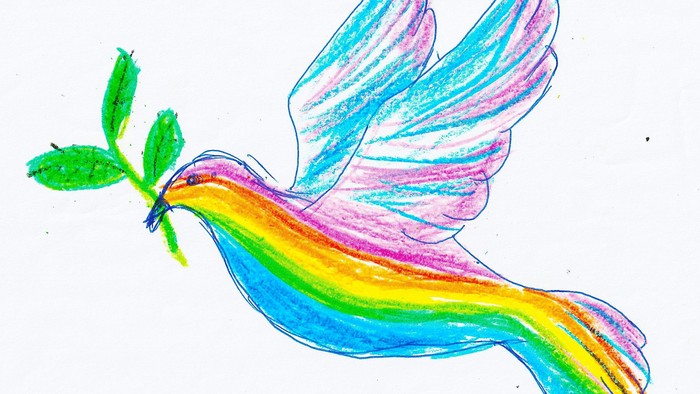 Bunte, verspielt wirkende Taube mit Regenbogenflügeln und grünen Blättern im Schnabel.