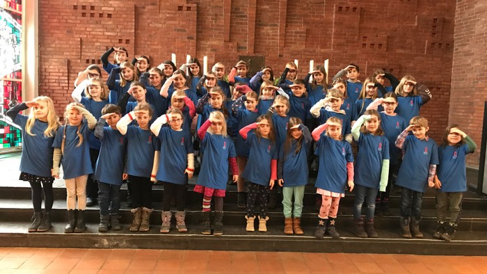 Gruppe von Kindern in blauen Uniformen vor Backsteinmauer