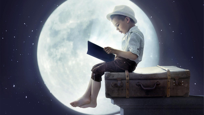 Ein Junge sitzt auf einem Koffer und liest ein Buch vor dem Vollmond.