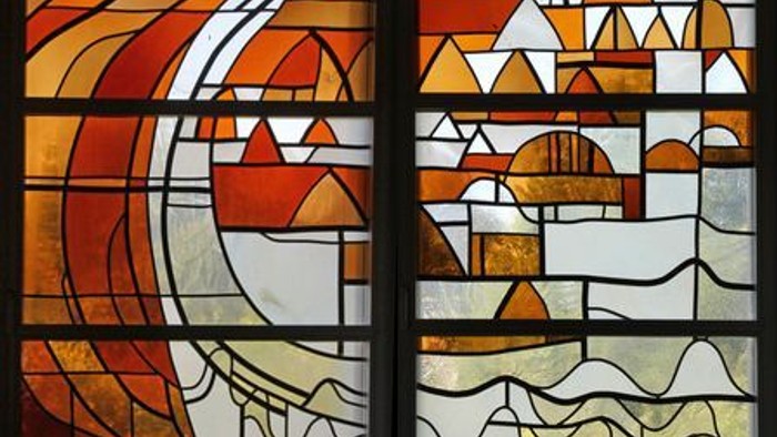 Buntglas-Kunst mit abstrakten geometrischen und organischen Mustern in warmen, erdigen Tönen.