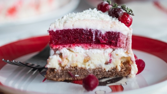 Ein Stück Erdbeerkuchen auf rotem Teller, mit Sahne und Erdbeeren