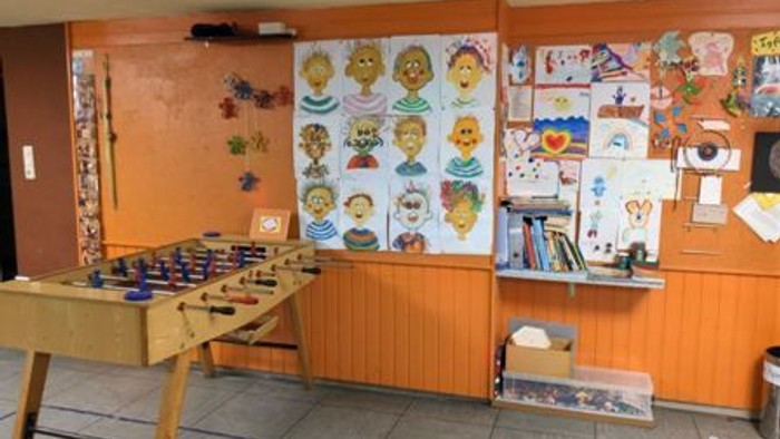 Kreatives Klassenzimmer mit farbenfrohen Schülerkunstwerken, Basteltisch und ausgestellten Lehrmaterialien.