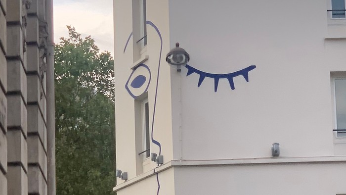 En blå kattefigur på væggen af et hvidt hus.
