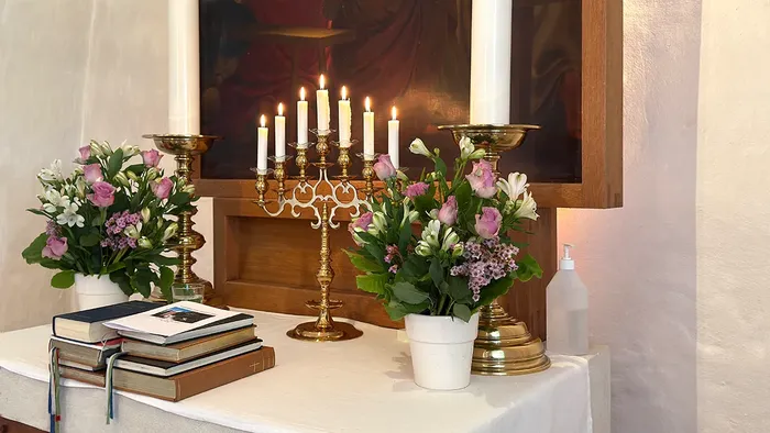 Alter med lilla blomster og 7 tændte lys