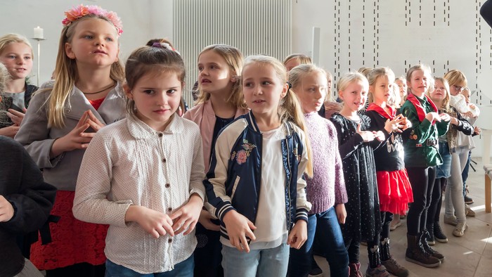 En lærer leder en gruppe unge elever i en interaktiv indendørs lektion eller aktivitet.