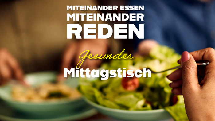 Menschen genießen gemeinsam ein gesundes Mittagessen mit frischem Salat und angeregten Gesprächen in einer gemütlichen Atmosphäre.