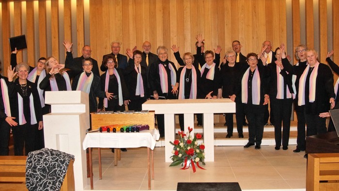 Ein Chor tritt in einer Kirche auf und hebt die Hände während eines Musik- oder Gottesdienstes.
