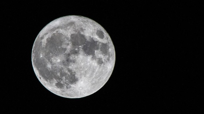 Ein großer, hell erleuchteter Vollmond vor dunklem Nachthimmel.