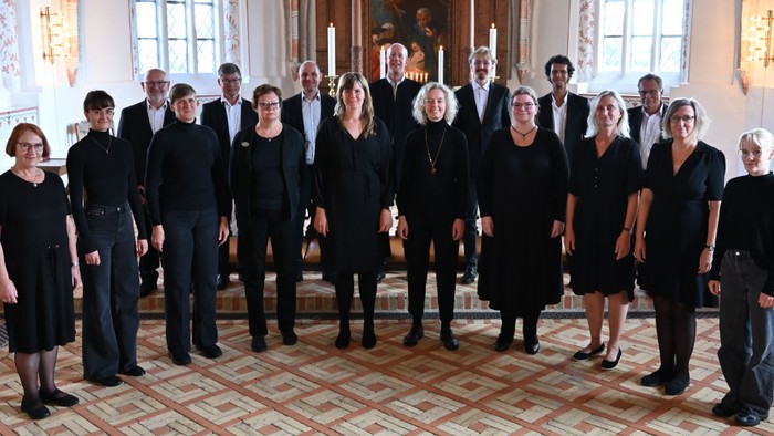 En formel korgruppe, der poser sammen i en elegant indendørs omgivelse med klassisk indretning.