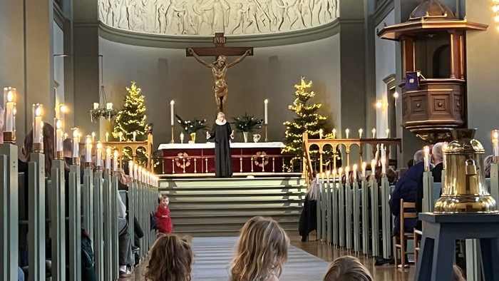 Tre børn sidder i en kirke.