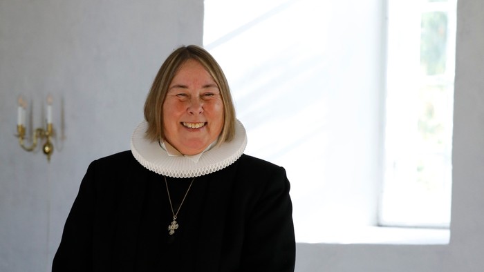 Præst eva Melhof står ved døbefont