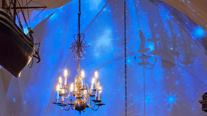 Religiøs ceremoni i en stor, blåoplyst kirke med præster, der synger, og prægtige dekorationer.