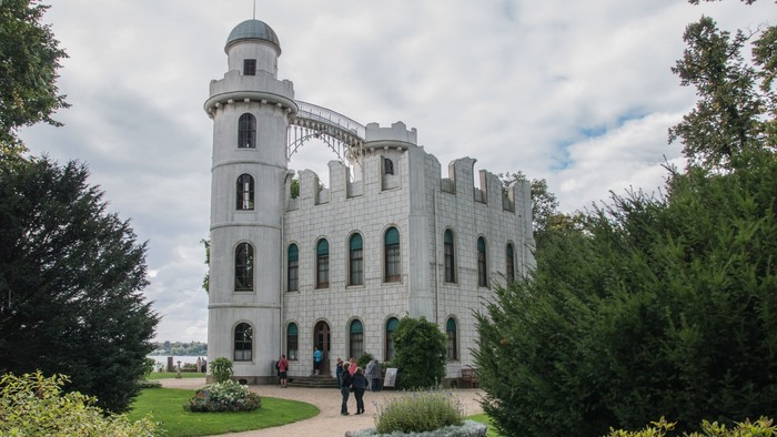 Ein prächtiges schlossartiges Gebäude mit einem spiralförmigen Turm, umgeben von einem üppigen, gepflegten Garten.