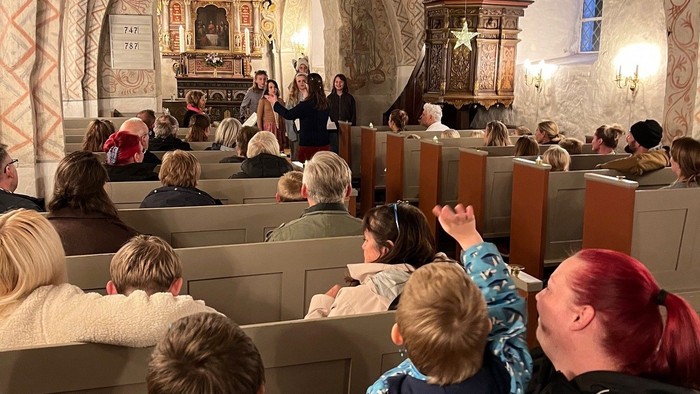 Kirke med kirkegængere der lytter til Børnekoret der synger.