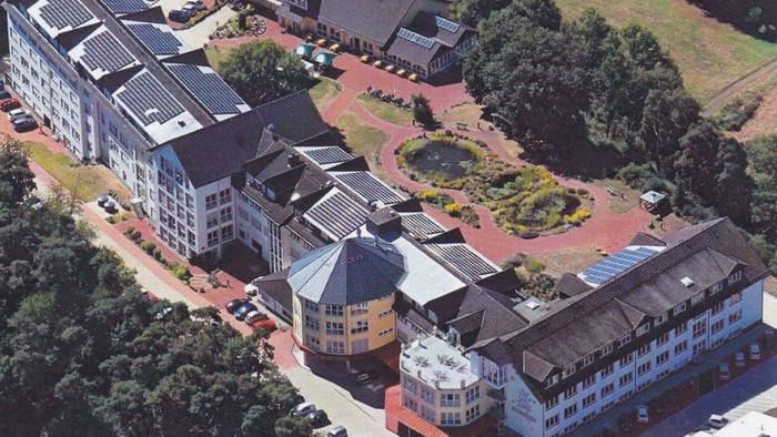 Luftaufnahme eines modernen Wohnkomplexes mit Gärten, Wegen und Solardächern.