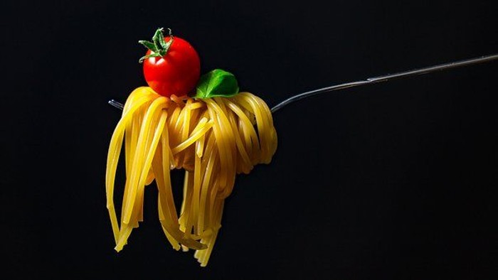 En gabel med spaghetti og tomat.