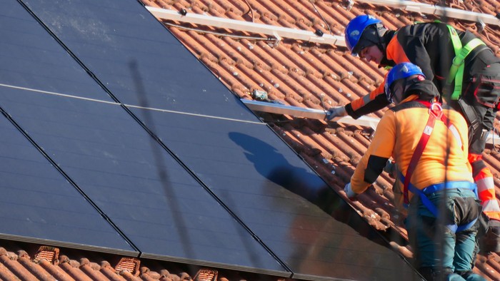 Zwei Leute montieren Solarpaneelen auf einem Dach